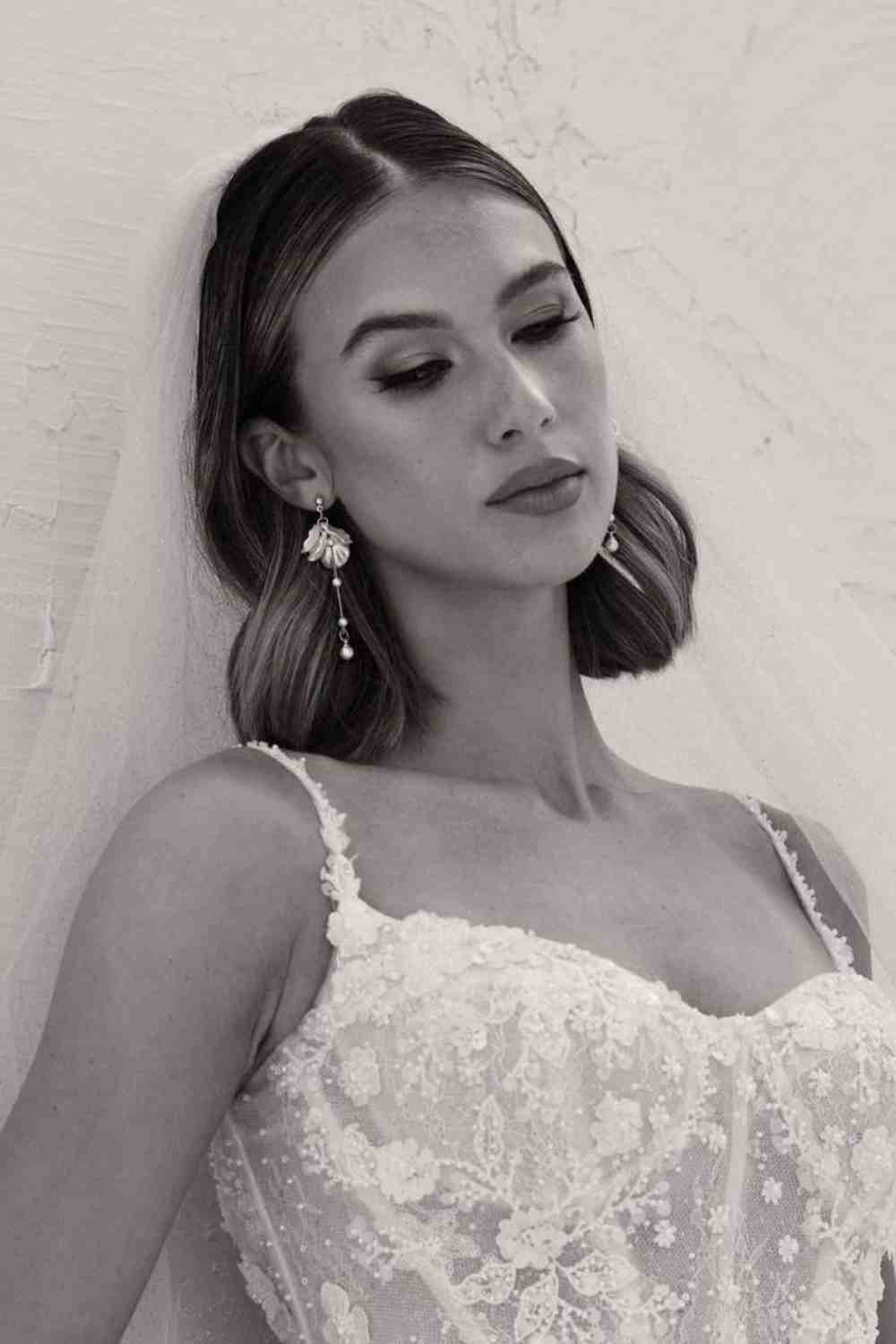 Honeymoonshop trouwjurk met sluier en elegante oorbellen.