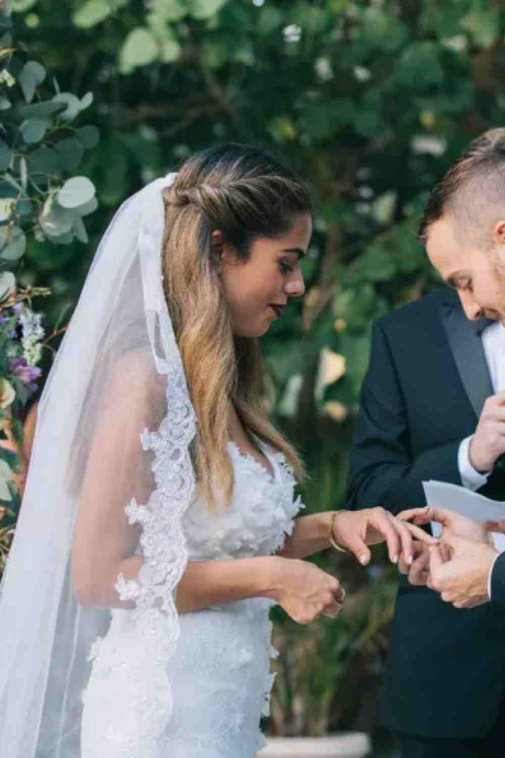 Bruidskapsel waarbij de voorste plukken in een twist naar achter zijn gestoken. De bruid draagt een sluier in haar halfopgestoken haar