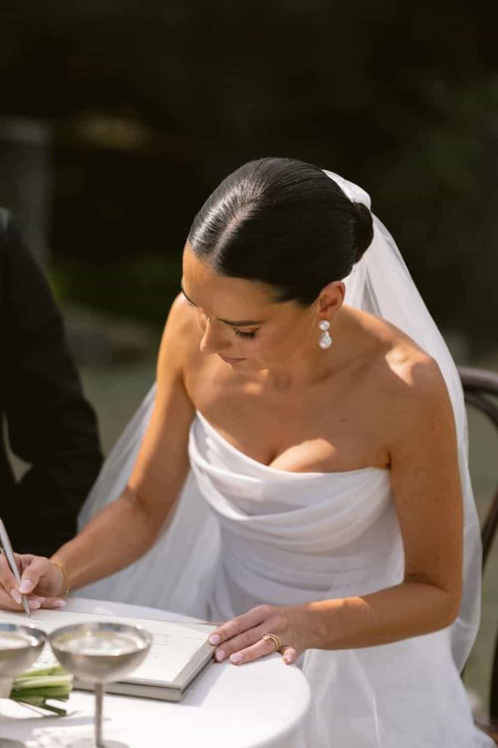Bruid met slicked back bun met middenscheiding en sluier.