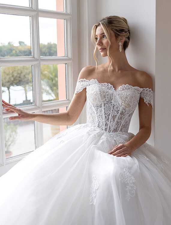Honeymoonshop, winkel, trouwjurken, trouwpakken, bruid in witte trouwjurk bij raam.
