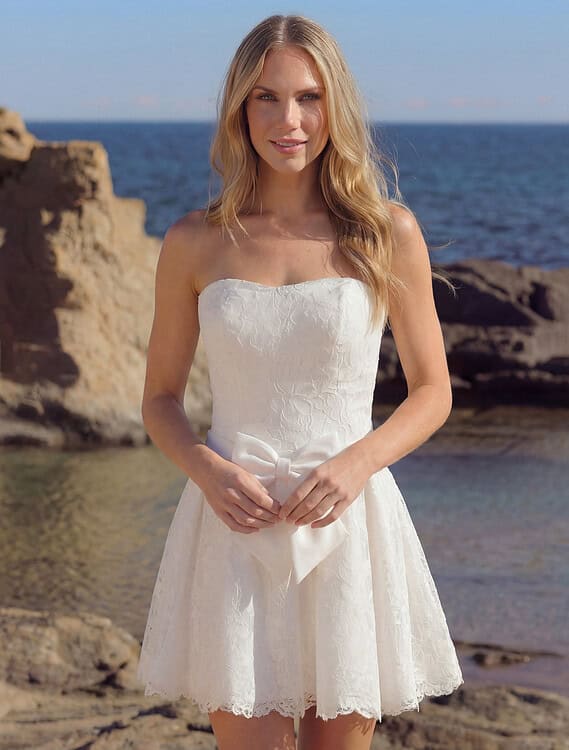 Honeymoonshop trouwjurk Hallie Azuree op strand met rotsen en zee.