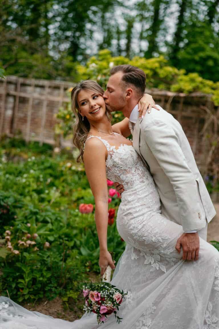 Honeymoonshop trouwjurken en trouwpakken voor bruiloft, romantisch paar in tuin.