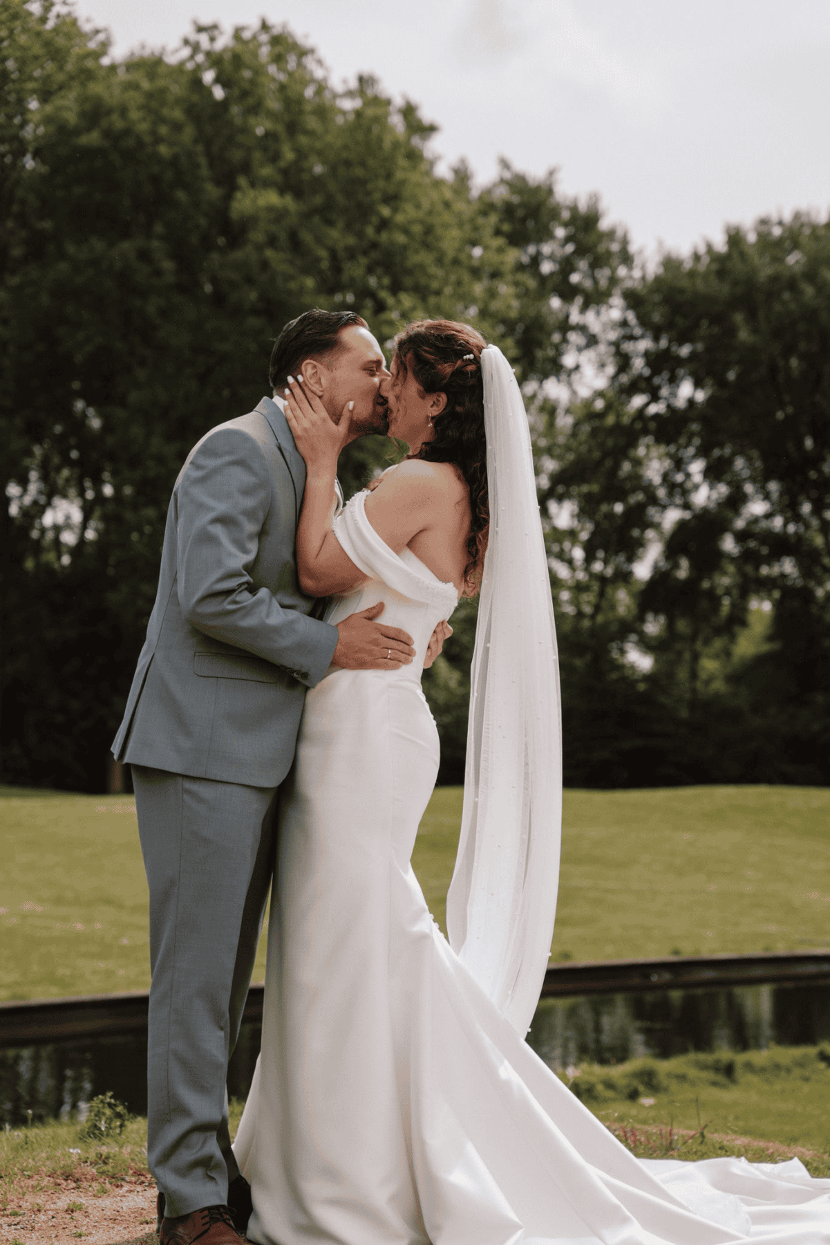 Liefdevol bruid en bruidegom kussen elkaar in de buitenlucht op hun huwelijksdag.