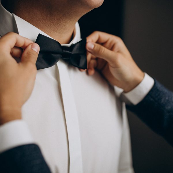 Groom dressing before the wedding ceremony, putting on a bow