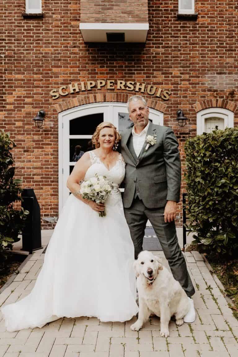 Lief bruidspaar met hond voor Honeymoonshop, trouwjurken, trouwpakken, winkel.